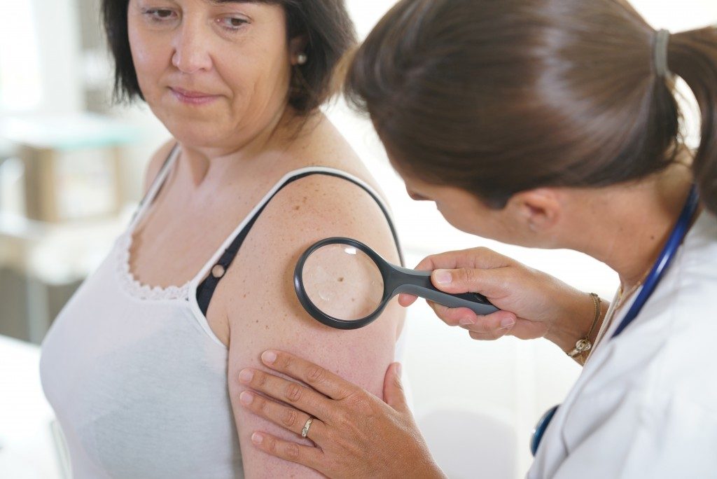 doctor examining skin of middle aged woman