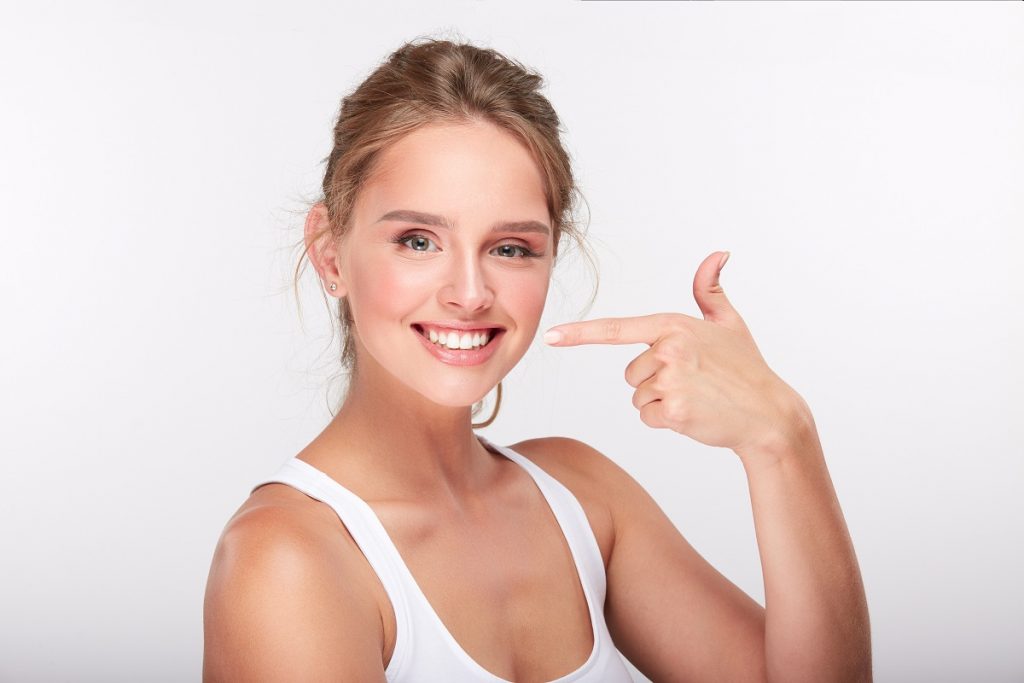 Woman smiling and pointing at her teeth