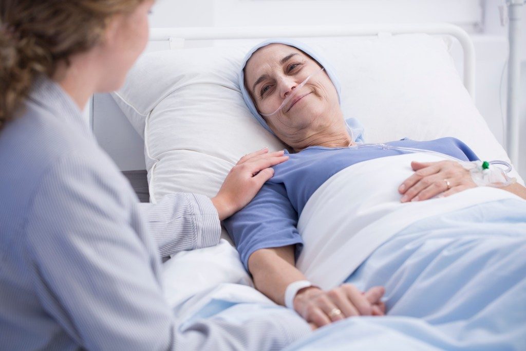 patient laid in bed smiling to her visitor