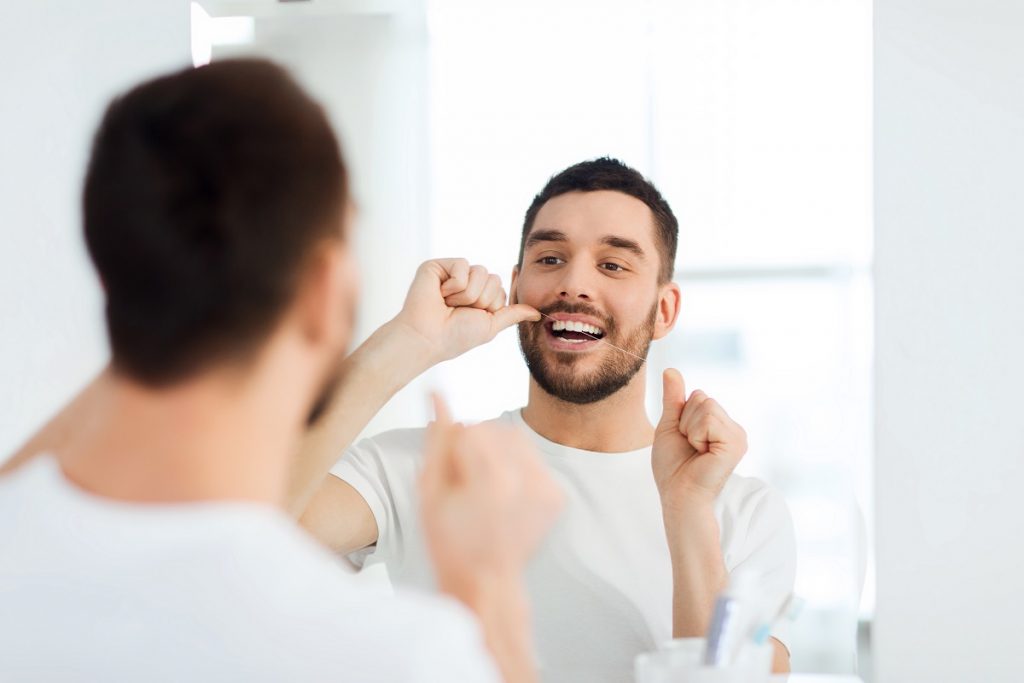 man flossing his teeth