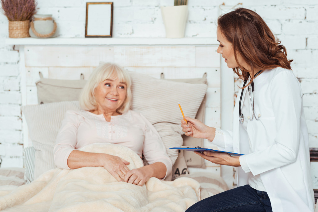 senior woman lying in bed while speaking to her doctor