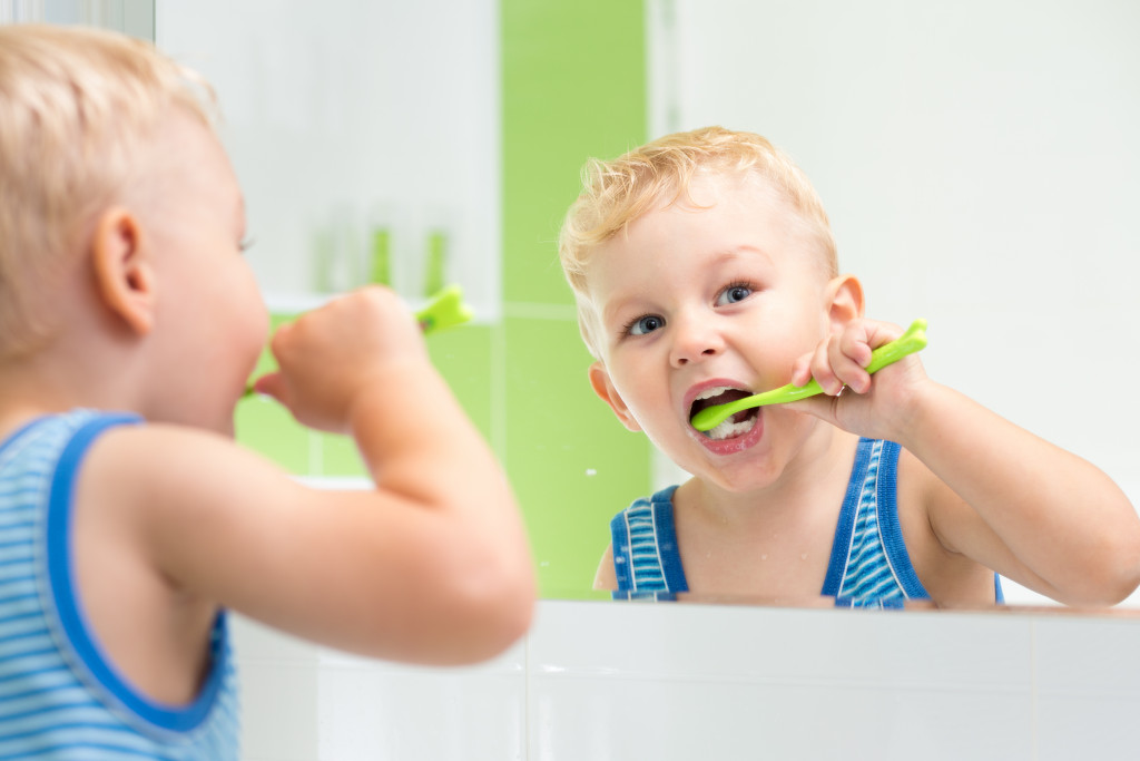 little boy brushing his teeth in front of the mirror