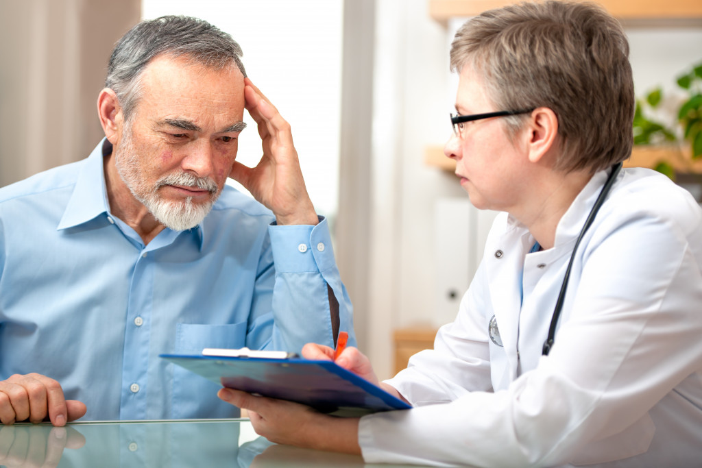 old man complaining to doctor about headache