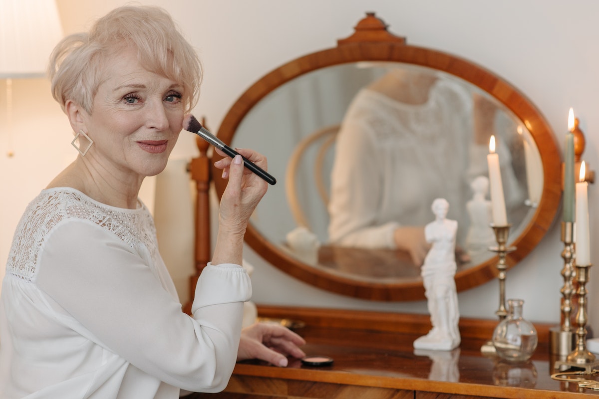 Photo of an Elderly Person Putting Makeup on Her Cheek