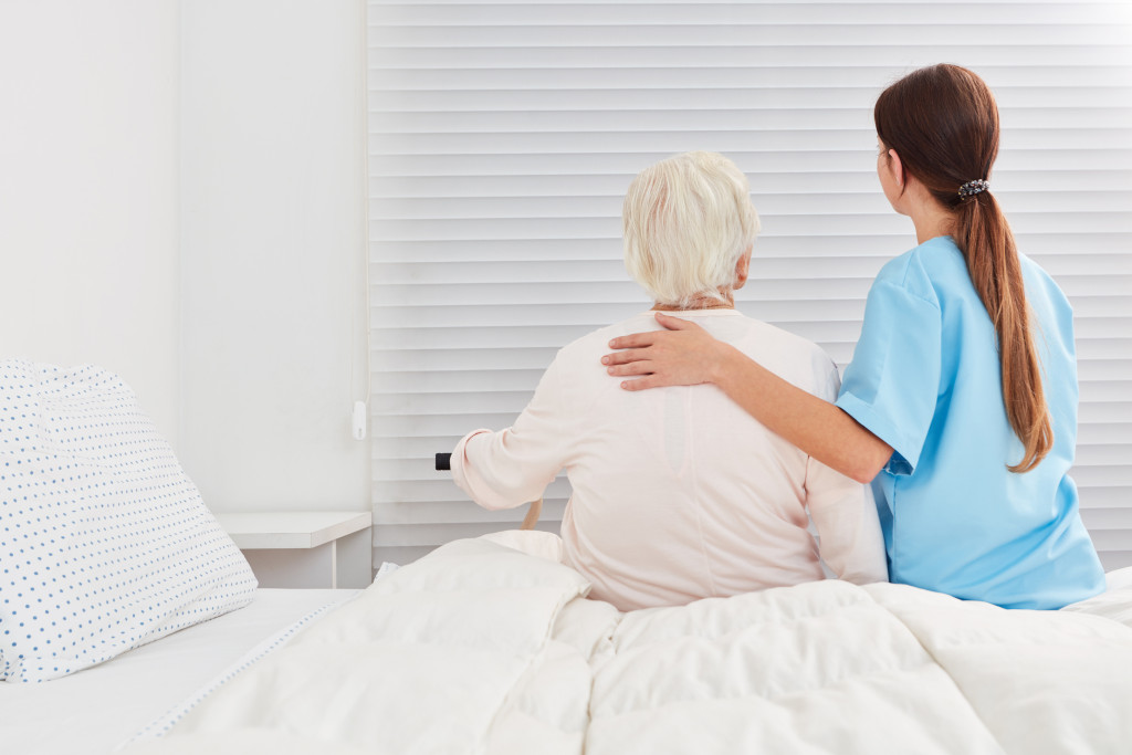 A caregiver helping a senior woman out of bed