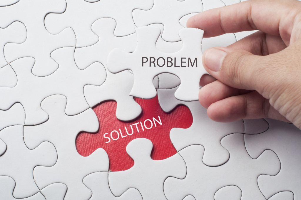 a hand holding a puzzle piece with problem written on it and below shows solution in red color