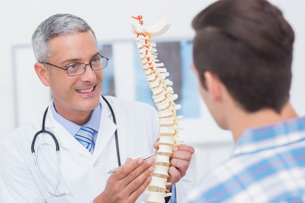 A doctor showing a spine model to a patient