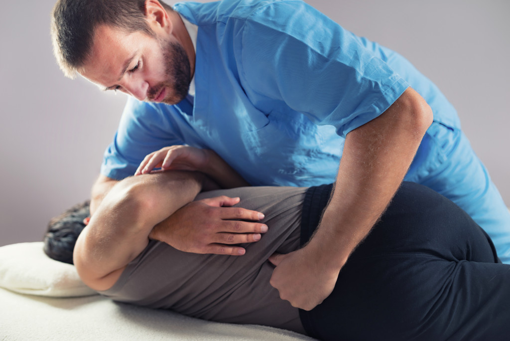 A chiropractor doing a healing treatment to a patient with back pain or injury inside the clinic
