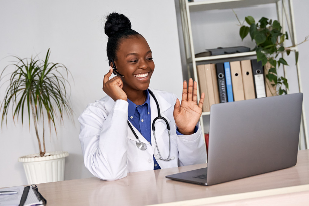 smiling female doctor talking to a patient via a laptop