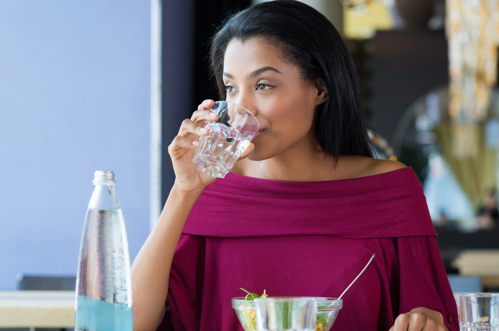 woman drinking water while eating
