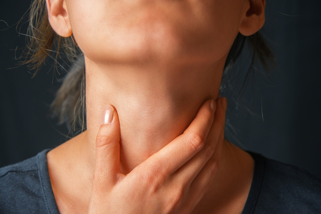 a close-up shot of a woman caressing her neck due to sore throat