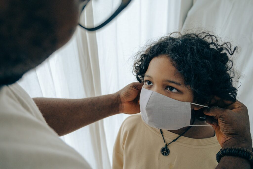 father putting medical mask on his son