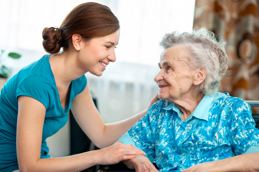 young woman smiling while talking to elderly woman in their home