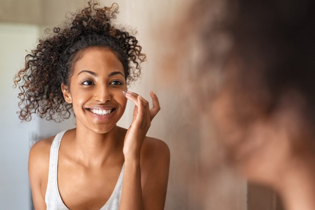woman applying moisturizing cream on her cheek