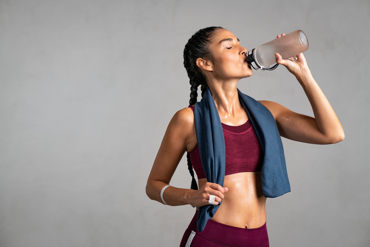 Young woman drinking water from a bottle after a workout.