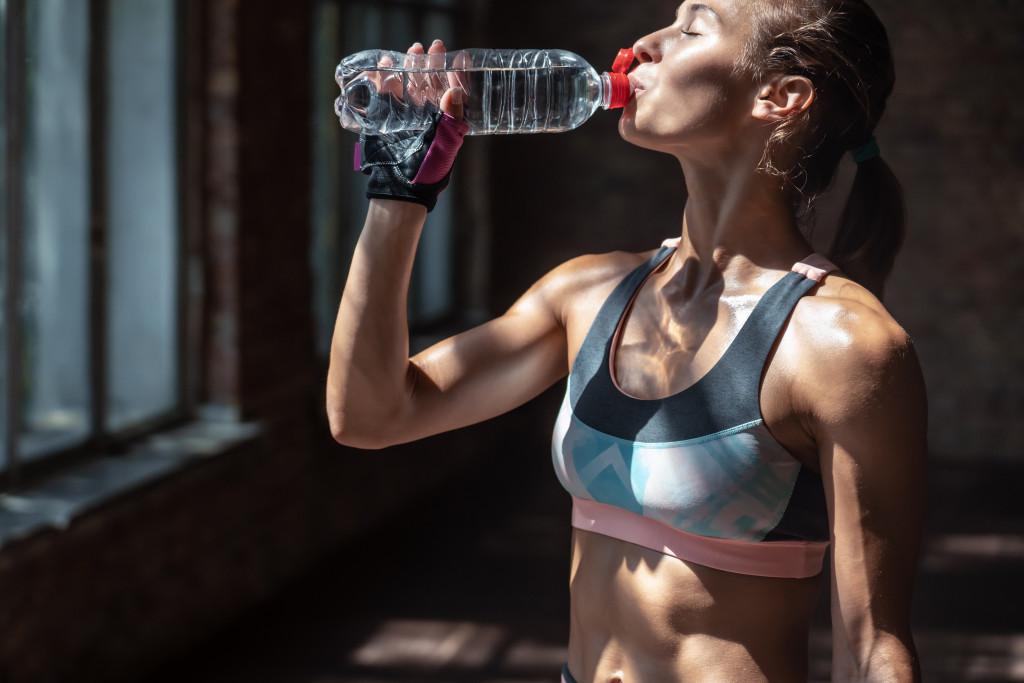 a fit woman drinkng water during workout
